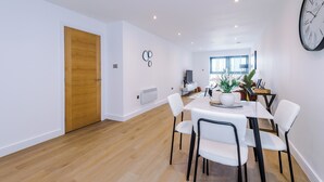 A modern dining area with a wooden door, white walls, and a clock. - Family Friendly Stay-Leeds City Centre With City View (Leeds)