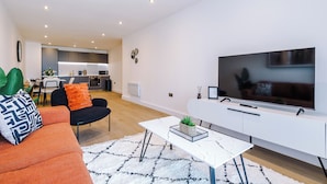 A modern living room with a sofa, a coffee table, and a TV. - Family Friendly Stay-Leeds City Centre With City View (Leeds)