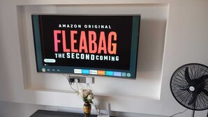 Televisão de tela plana fixada na parede exibindo 'Amazon Original Fleabag The Second Coming'.