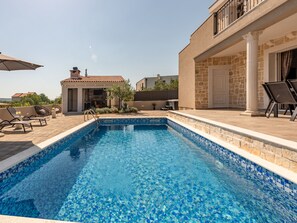 A swimming pool with a tiled edge, surrounded by lounge chairs and a patio area. - Holiday Home Solea with pool by Interhome (Zadar/Bibinje)