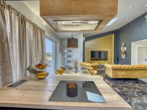 A modern living room with a dining area, a fireplace, and a large TV. - Holiday Home Solea with pool by Interhome (Zadar/Bibinje)