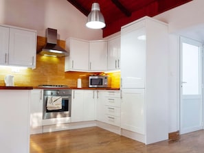 A modern kitchen with white cabinetry, a stainless steel oven, a microwave, and a hanging light fixture. - Beachfront Villa Dream with pool by Interhome (Blato)