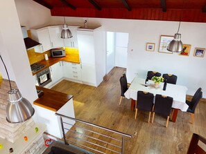 A modern kitchen with white cabinets, a microwave, and a gas stove. There is a dining area with a table and chairs, and a staircase leading to an upper level. - Beachfront Villa Dream with pool by Interhome (Blato)