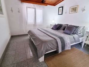 A bedroom with a bed, bedside tables, a window with blinds, and wall-mounted artwork. - Beachfront Villa Dream with pool by Interhome (Blato)