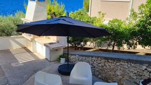 Eine Terrasse im Freien mit Tisch, Stühlen und einem großen Sonnenschirm.