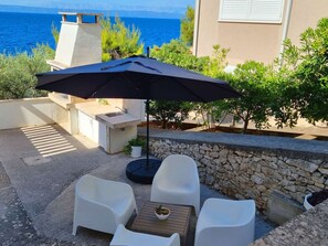 An outdoor patio with a table, chairs, and a large umbrella. - Vacation home  by Interhome (Blato)