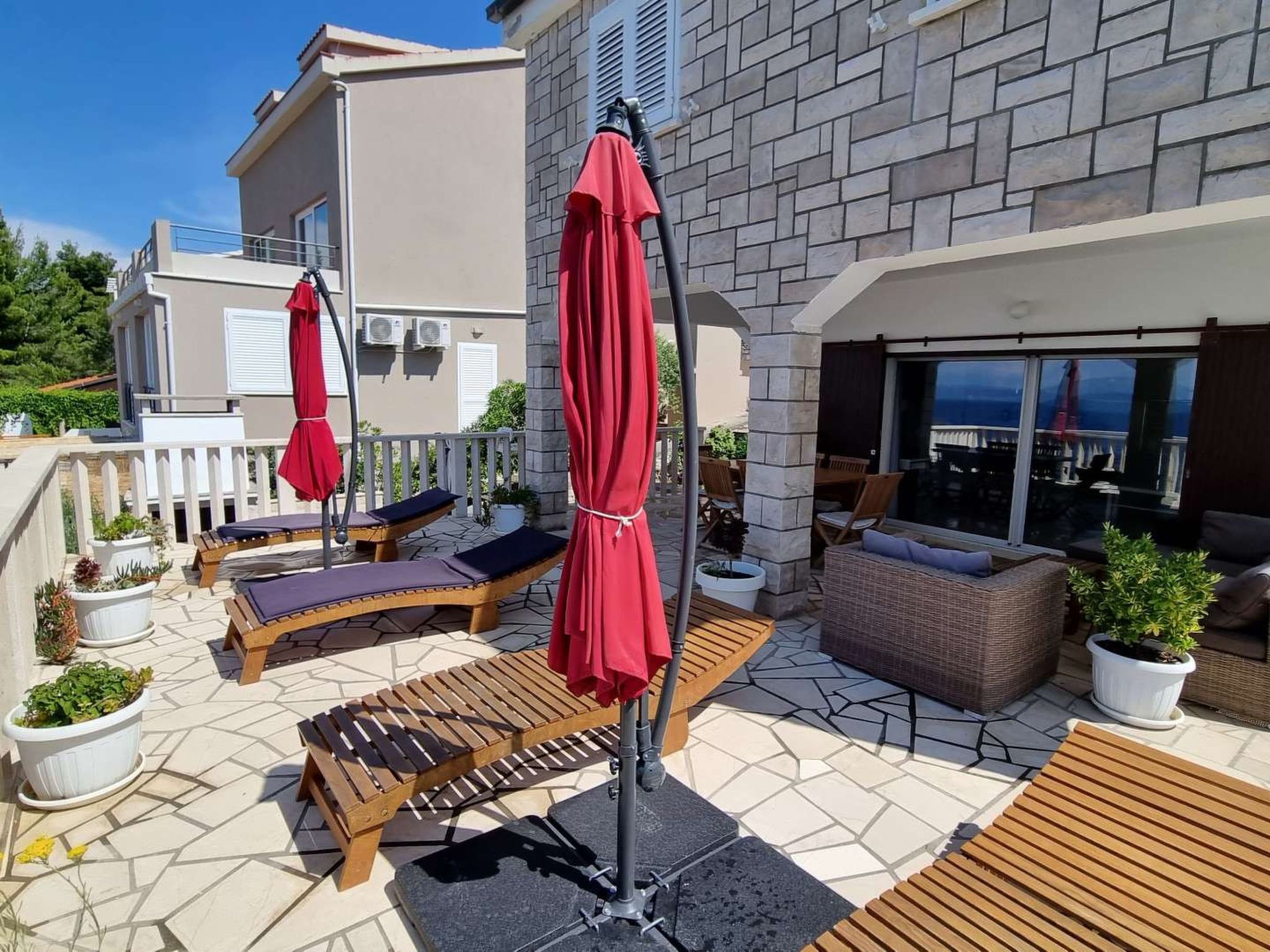 Eine Dachterrasse mit Sitzgelegenheiten im Freien, einer Pergola und Blick aufs Meer.