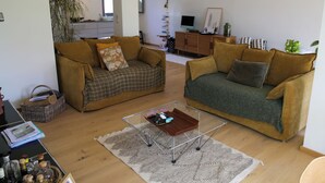 Ett vardagsrum med två soffor, ett soffbord, en bokhylla och en tv.