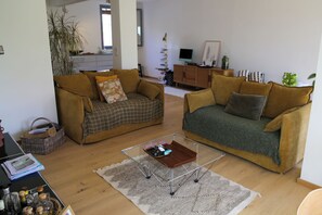 Ein Wohnzimmer mit zwei Sofas, einem Couchtisch, einem Bücherregal und einem Fernseher.