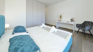 Ett modernt sovrum med en stor säng, ett skrivbord och en stol.