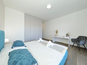 A modern bedroom with a large bed, a desk, and a chair. - Vacation home  by Interhome (Vrsi)