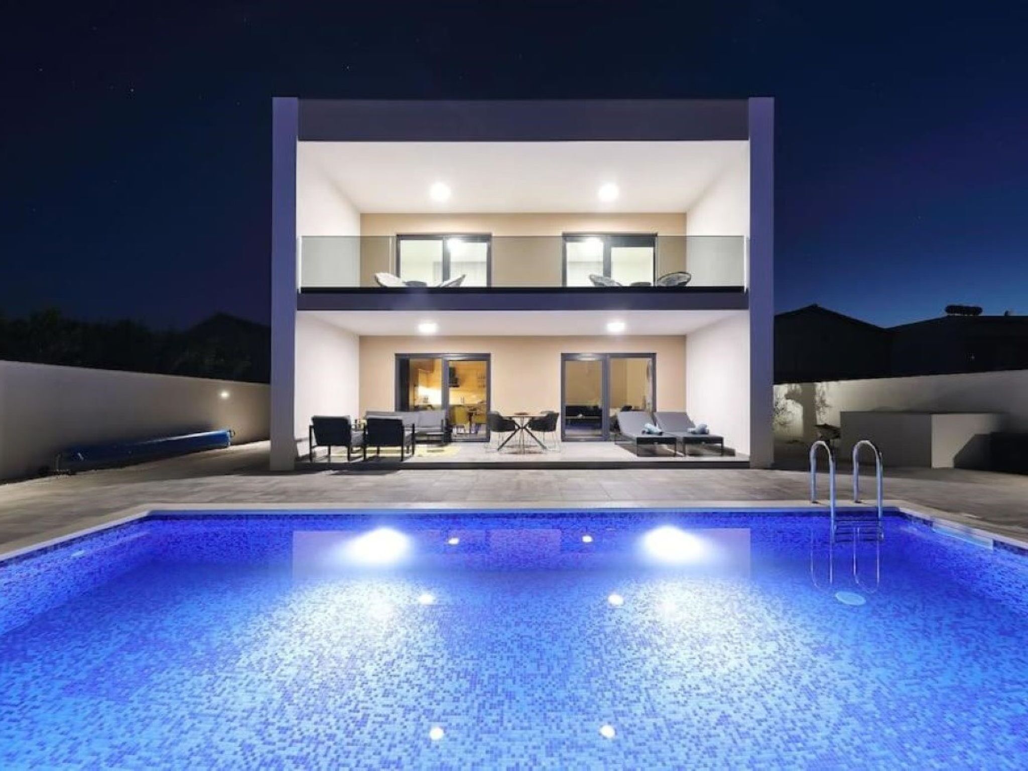 A modern two-story building with a swimming pool in the foreground.