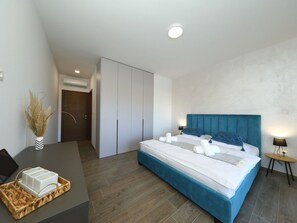 A modern hotel room with a large bed, a desk with a basket, a chair, and a small table with a lamp. - Villa Good Vibes with heated pool by Interhome (Vrsi)