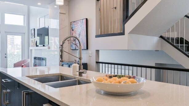 A modern kitchen with a large island, stainless steel appliances, and a bowl of fruit.