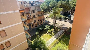 A residential area with multi-story buildings, a central courtyard with trees, and a clear sky.