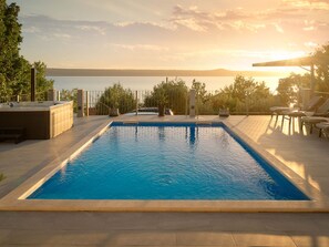 A rectangular swimming pool with a view of the sea and a sunset in the background. - Beautiful Villa Katharina with pool by Interhome (Rovanjska)