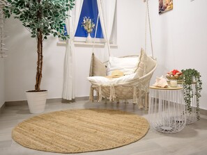 A room with a hanging chair, a round woven rug, a potted plant, and a small round table with a candle and a basket. - Beautiful Villa Katharina with pool by Interhome (Rovanjska)