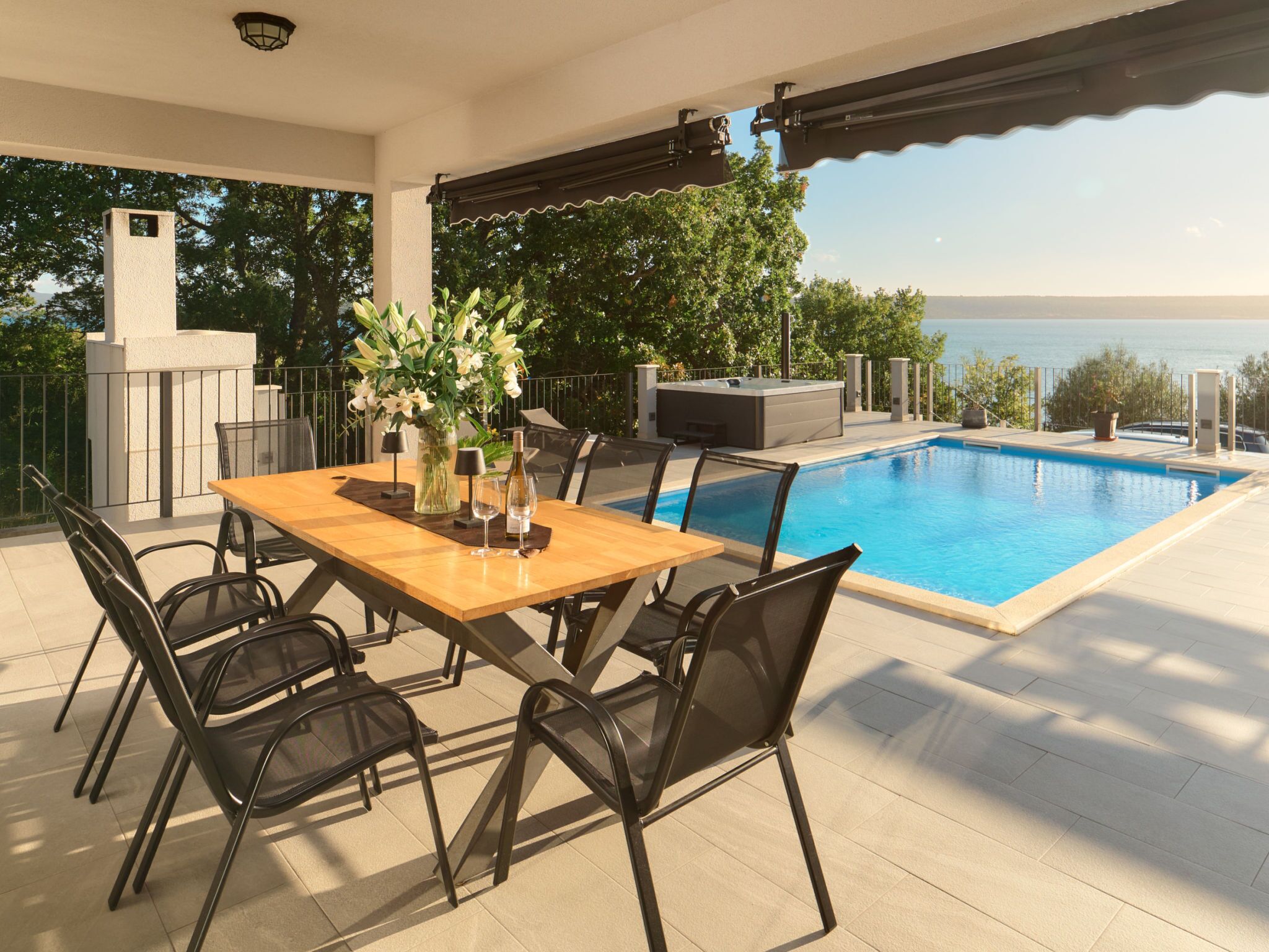 Un espace extérieur avec une piscine, une table à manger et des chaises, le tout entouré d’une terrasse aménagée autour de la piscine.