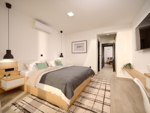 Ein modernes Schlafzimmer mit Bett, Nachttischen, einem Schreibtisch und einem Fernseher.
