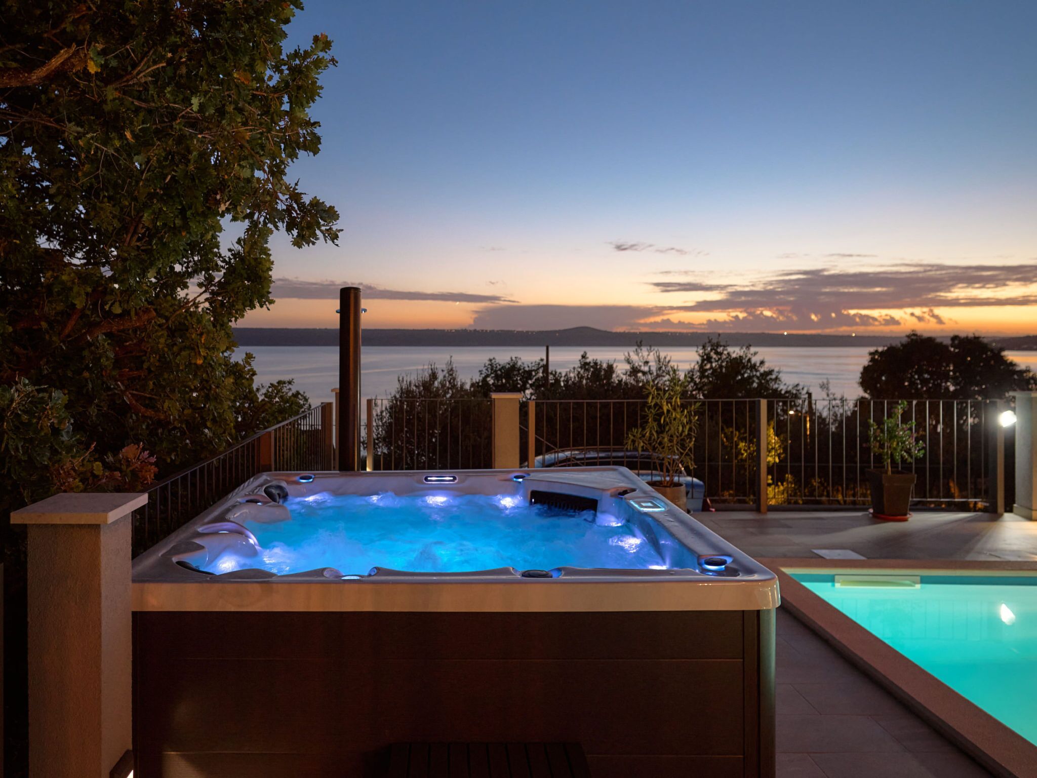 A hot tub with a view of the sea at dusk.