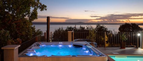 A hot tub with a view of the sea at dusk.