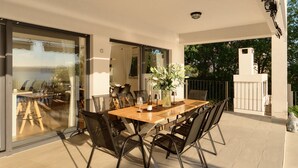 A dining area with a table and chairs, a vase with flowers, and a view through glass doors. - Vacation home  by Interhome (Rovanjska)