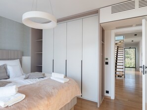 Ein modernes Schlafzimmer mit Bett, Einbauschrank und einer Treppe, die in einen weiteren Bereich führt.