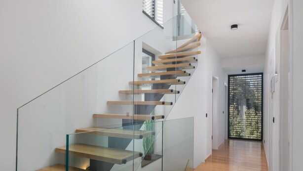 A modern staircase with glass railings and wooden steps, leading to a room with a view of greenery. - Villa Acacia with heated pool by Interhome (Petrčane)
