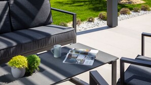 A modern outdoor seating area with a sofa, a table, a magazine, a mug, and a small plant. - Villa Acacia with heated pool by Interhome (Petrčane)