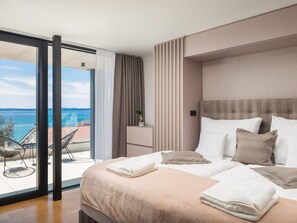 Una camera d'hotel con un letto, un comodino, una sedia e vista mare.