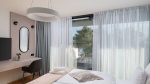 A modern bedroom with a bed, a desk, a chair, a television, and a large window with curtains. - Villa Acacia with heated pool by Interhome (Petrčane)