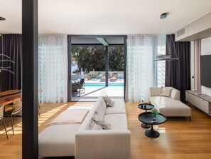 Ein modernes Wohnzimmer mit einer Couch, einem Couchtisch und Blick auf einen Swimmingpool.