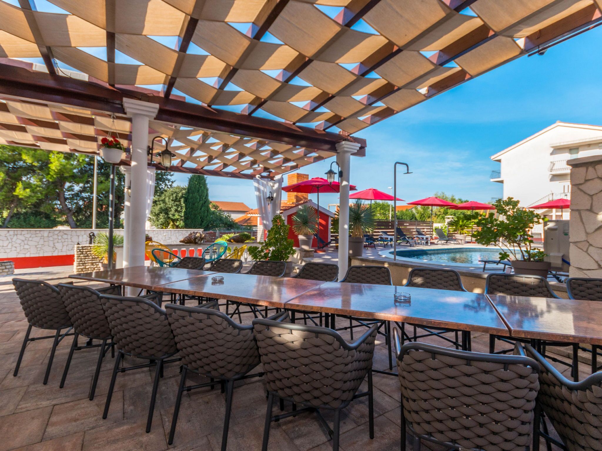 An outdoor patio with a pool, covered seating area, and a view of the surrounding buildings.