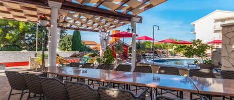 An outdoor patio with a pool, covered seating area, and a view of the surrounding buildings.