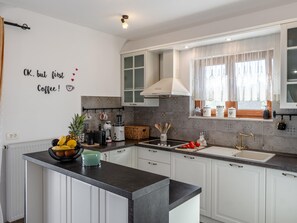 A modern kitchen with white cabinets, a black countertop, and a decorative wall sign. - Holiday Home Beti with heated pool by Interhome (Vrsi)
