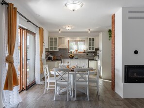 A modern kitchen with white cabinets, a dining table with chairs, and a fireplace. - Holiday Home Beti with heated pool by Interhome (Vrsi)