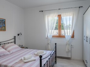 A bedroom with a bed, a radiator, a window with curtains, and a painting on the wall. - Holiday Home Beti with heated pool by Interhome (Vrsi)