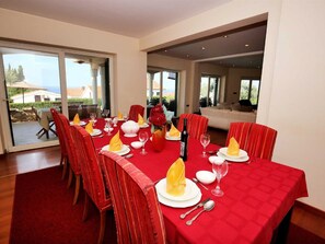 A dining area with a red tablecloth, white plates, and red chairs. - Vacation home  by Interhome (Petrčane)