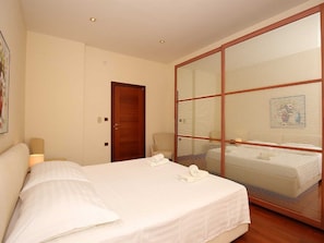 Quarto de hotel com cama, uma cadeira, uma escrivaninha e uma grande porta de vidro deslizante.