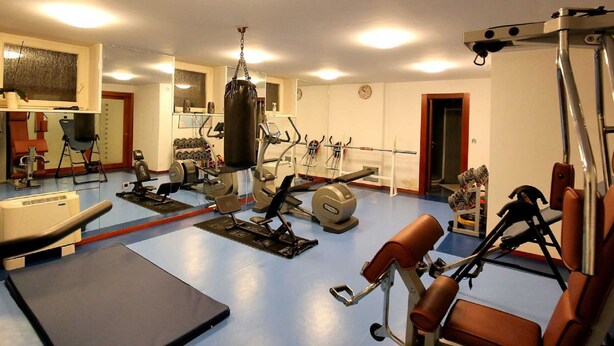 Ett gym med olika typer av träningsutrustning, inklusive en boxningssäck, styrketräningsmaskiner och lösa vikter.