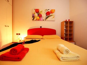 A hotel room with a bed, a nightstand, a lamp, a painting, and a wooden cabinet. - Vacation home  by Interhome (Petrčane)
