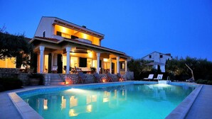 En modern villa med pool, utomhusmöbler och en väl upplyst uteplats.