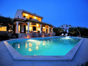 A modern villa with a swimming pool, outdoor seating, and a well-lit patio area. - Vacation home  by Interhome (Petrčane)