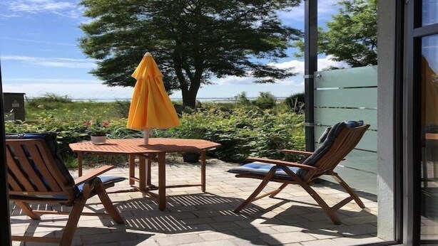 Une terrasse extérieure avec une table, des chaises et un parasol jaune.