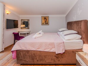 Une chambre à coucher avec un lit, un bureau, une chaise, un téléviseur et un tableau accroché au mur.