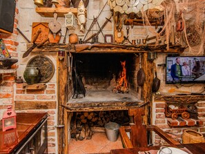 A rustic fireplace with a TV mounted above it, surrounded by various antique items and tools. - Vacation home  by Interhome (Rovanjska)
