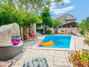 Une piscine avec des chaises longues et un espace de détente abrité.