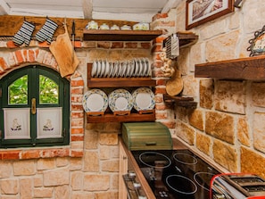 A kitchen with a brick wall, wooden shelves, and various kitchen utensils. - Rustical Villa Verde with pool by Interhome (Rovanjska)