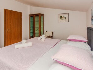 Un dormitorio con cama, armario de madera, una silla y un cuadro en la pared.