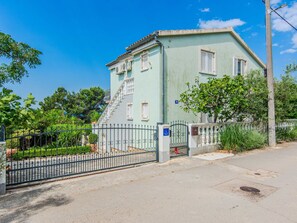Un bâtiment à deux étages, doté d’une façade vert clair, d’une grille en métal et d’un escalier menant à l’entrée.